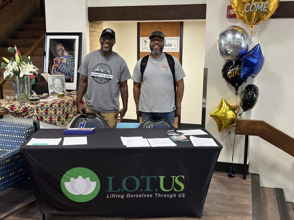LOTUS at an expo with a table. the founders are posing for the camera